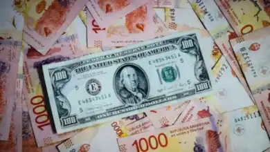 A hundred dollar bill is laying on top of a pile of money.